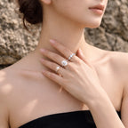 Close-up of a model wearing a white pearl ring with an eight-pointed star motif and sparkling cubic zirconia rings.