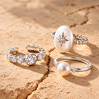 Starlight Aura Meteorite Galaxy three-piece ring set with a star pearl ring, pearl solitaire ring, and sparkling zirconia band on a warm beige background.